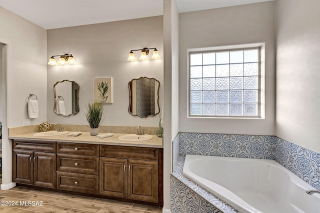 bathroom featuring tiled tub and vanity