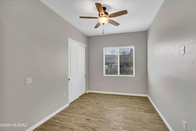 unfurnished bedroom featuring a closet, light hardwood / wood-style floors, and ceiling fan