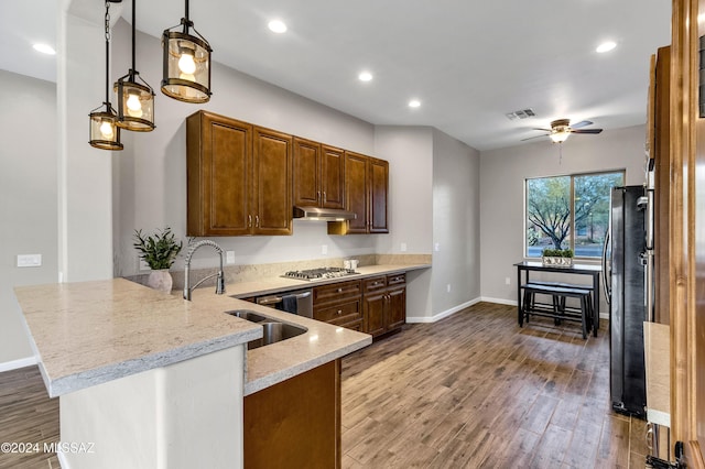 kitchen featuring black fridge, sink, ceiling fan, light stone countertops, and kitchen peninsula