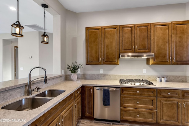 kitchen featuring light stone countertops, stainless steel appliances, hanging light fixtures, and sink