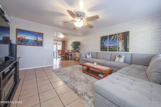 tiled living room featuring ceiling fan and brick wall