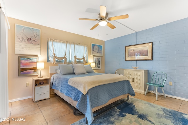 tiled bedroom featuring ceiling fan and brick wall