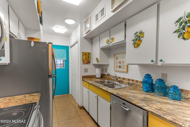 kitchen with sink, appliances with stainless steel finishes, light tile patterned flooring, light stone counters, and white cabinetry