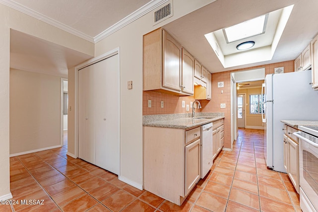 kitchen featuring light brown cabinetry, white dishwasher, a skylight, and sink