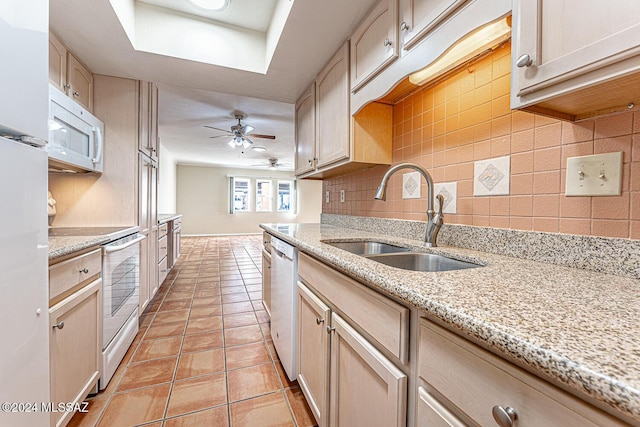 kitchen featuring light brown cabinetry, white appliances, and sink