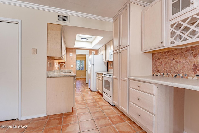 kitchen featuring a skylight, white appliances, sink, and tasteful backsplash