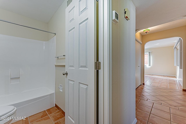 bathroom featuring tile patterned floors, toilet, and shower / washtub combination