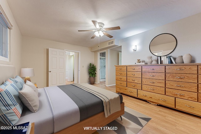 bedroom featuring ceiling fan, light wood-type flooring, and a textured ceiling