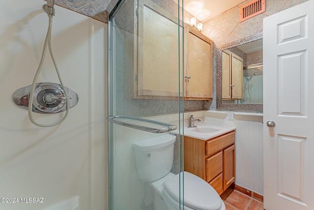 bathroom with tile patterned flooring, vanity, toilet, and walk in shower