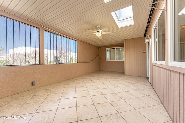 spare room with a skylight, ceiling fan, light tile patterned floors, and wood ceiling