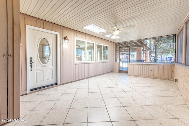 unfurnished sunroom featuring a skylight, ceiling fan, and wooden ceiling