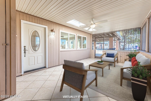 sunroom featuring a skylight, ceiling fan, and wooden ceiling