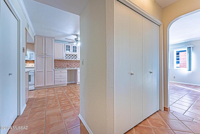 corridor with crown molding and light tile patterned flooring