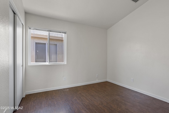 unfurnished room with dark wood-type flooring