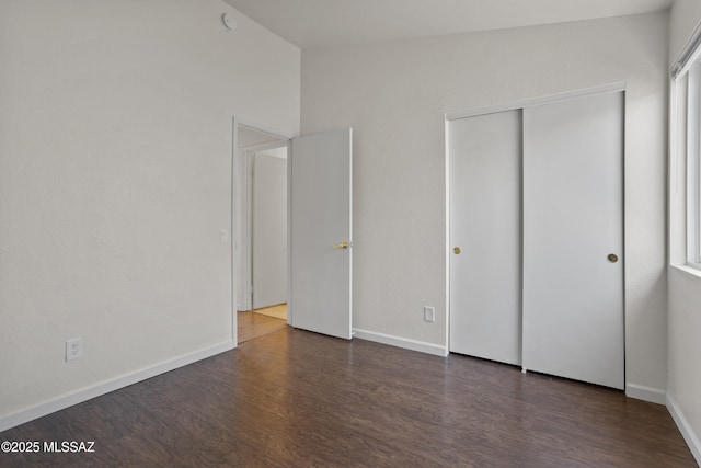 unfurnished bedroom featuring dark wood-type flooring and a closet