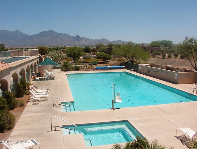 view of swimming pool featuring a mountain view, a community hot tub, and a patio area