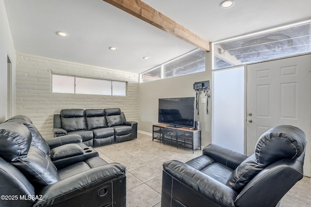 living room with vaulted ceiling with beams, light tile patterned floors, and brick wall