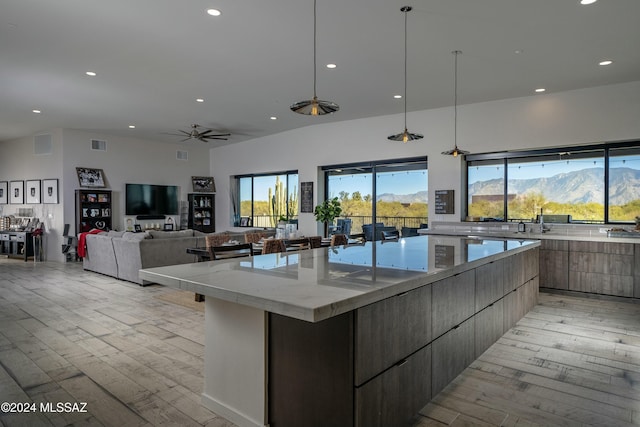 kitchen featuring hanging light fixtures, a large island, light stone counters, ceiling fan, and a mountain view