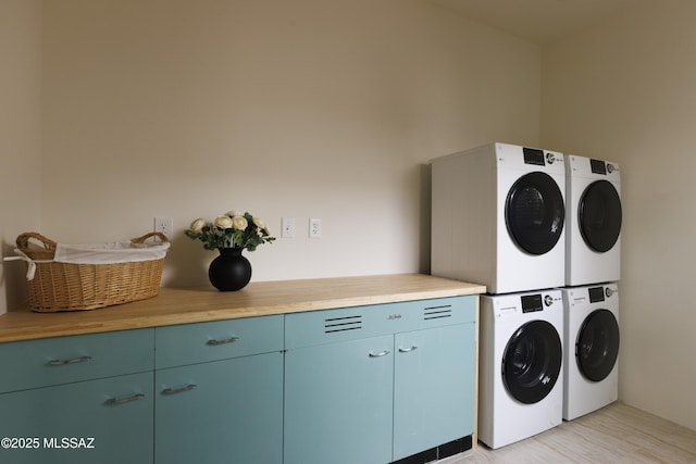 washroom with light hardwood / wood-style floors, cabinets, stacked washing maching and dryer, and washing machine and clothes dryer