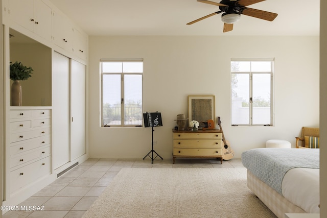 bedroom featuring multiple windows, ceiling fan, and light tile patterned flooring