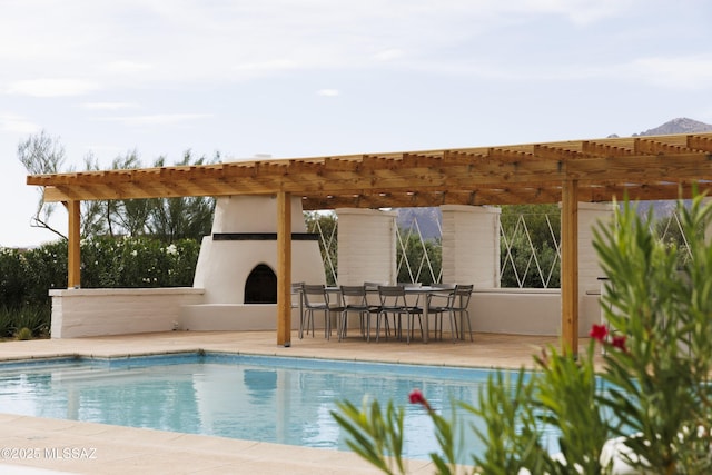 view of swimming pool featuring a pergola, an outdoor bar, a patio, and exterior fireplace