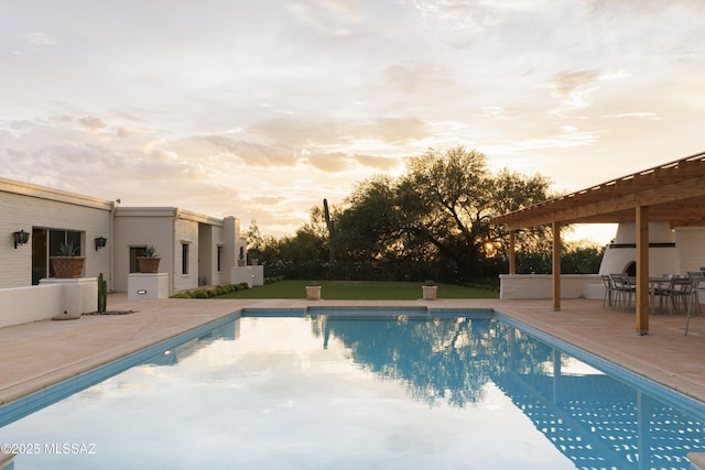 pool at dusk featuring a patio