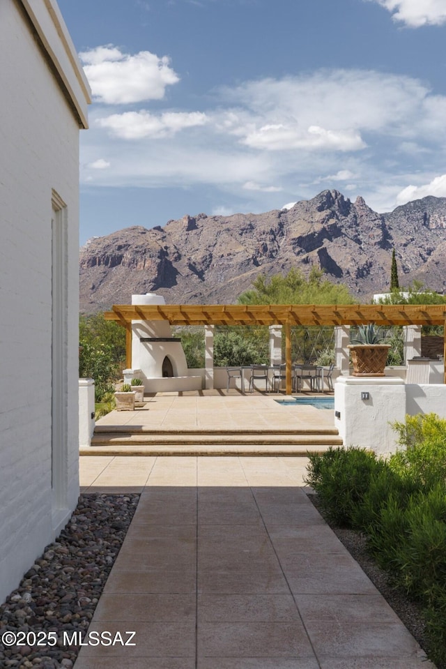 view of patio / terrace with a mountain view and exterior fireplace