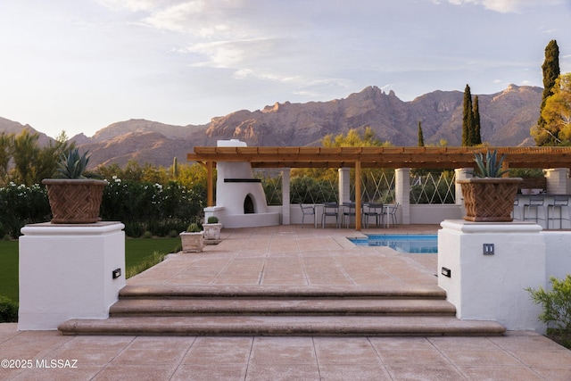 view of pool featuring a mountain view, an outdoor bar, a patio, and exterior fireplace