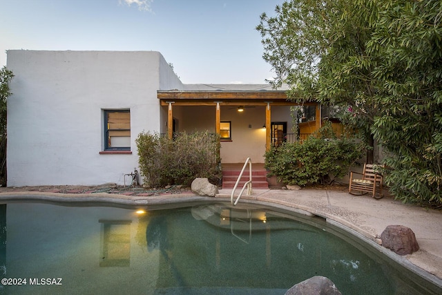 pool at dusk with a patio area