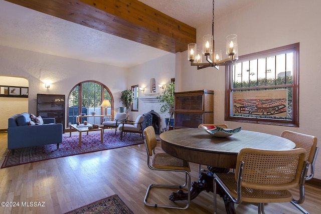 dining room featuring hardwood / wood-style flooring, a textured ceiling, beamed ceiling, and an inviting chandelier