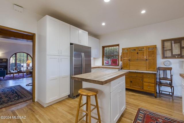 kitchen featuring stainless steel fridge, white cabinets, wooden counters, and a kitchen island