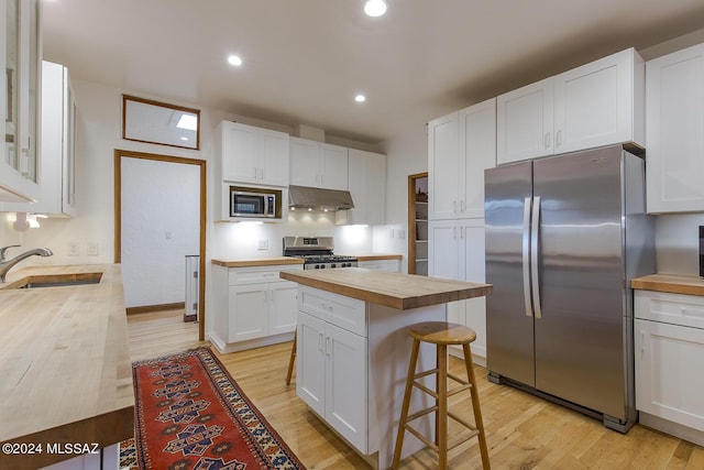 kitchen with wood counters, sink, white cabinetry, and stainless steel appliances