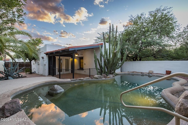 pool at dusk with a patio area