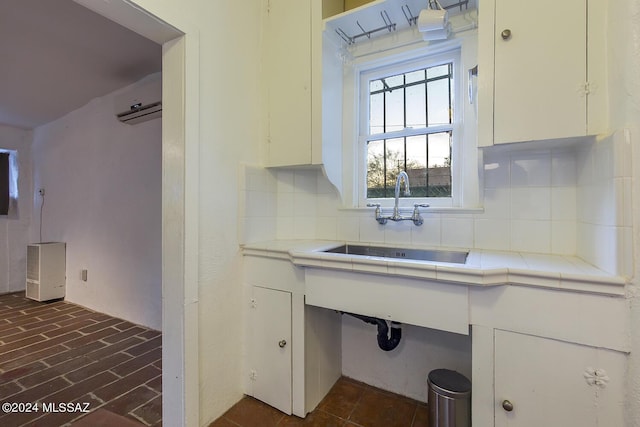 kitchen featuring tasteful backsplash, tile counters, white cabinets, and sink