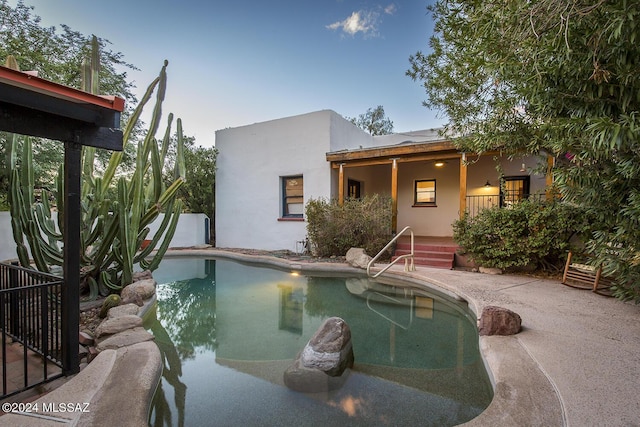 pool at dusk with a patio area