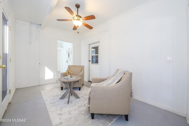 sitting room featuring ceiling fan, beam ceiling, and crown molding