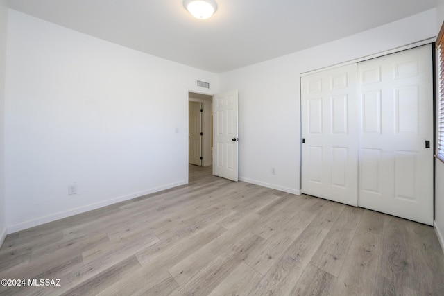 unfurnished bedroom featuring light wood-type flooring and a closet