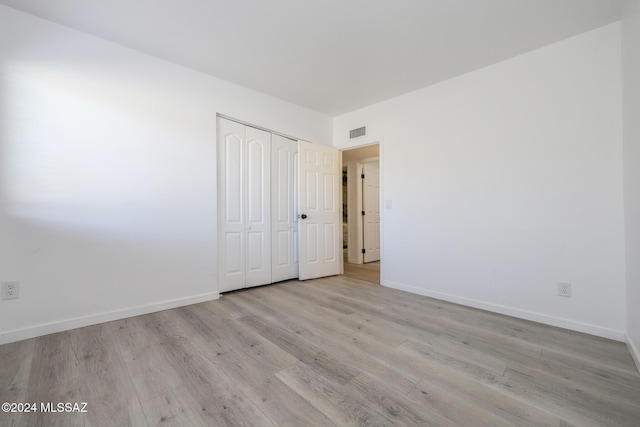 unfurnished bedroom with light hardwood / wood-style flooring and a closet