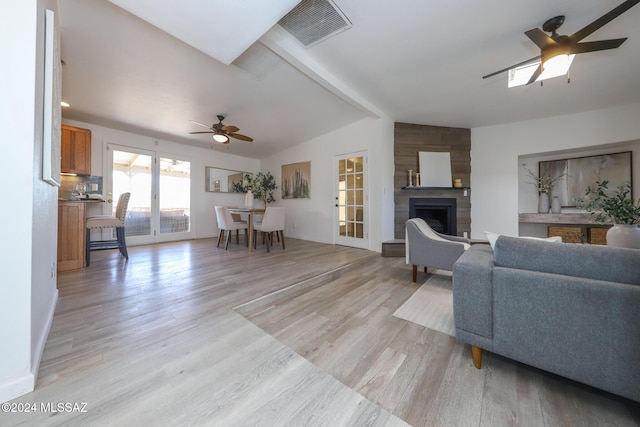 living room with lofted ceiling with beams, ceiling fan, a fireplace, and light hardwood / wood-style floors