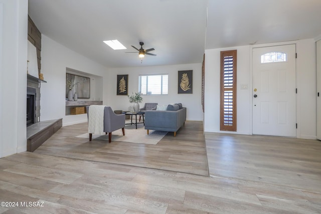 entrance foyer with a fireplace, light wood-type flooring, ceiling fan, and lofted ceiling