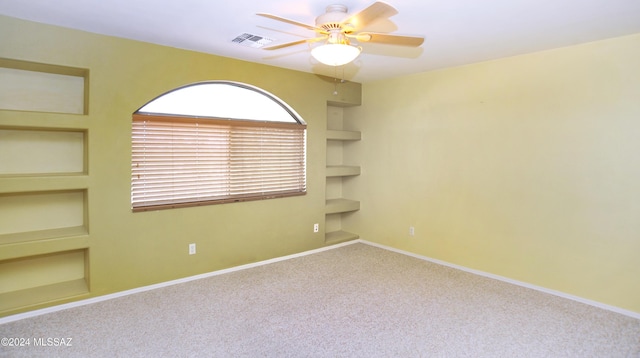 carpeted spare room with ceiling fan and built in features