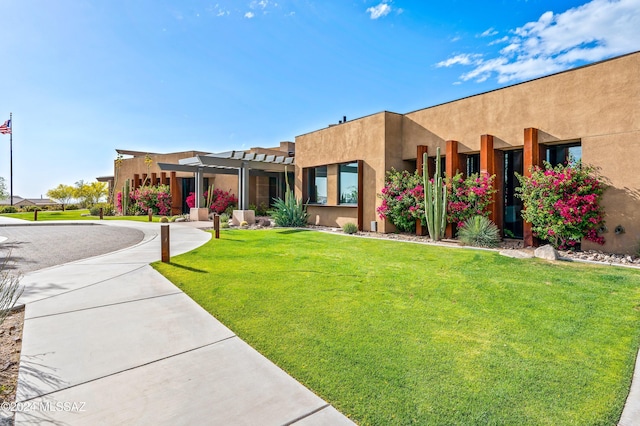 pueblo revival-style home featuring a pergola and a front lawn