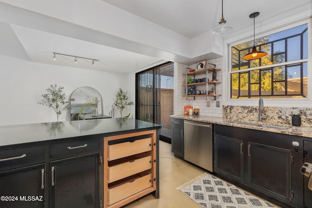 kitchen featuring tasteful backsplash, sink, light tile patterned floors, decorative light fixtures, and dishwasher