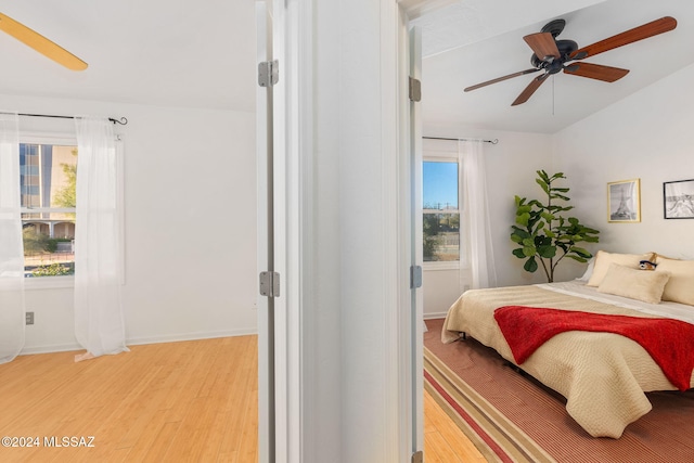 bedroom with multiple windows, ceiling fan, and hardwood / wood-style floors