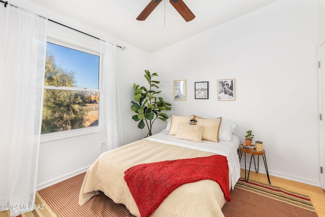 bedroom with multiple windows, hardwood / wood-style flooring, and ceiling fan