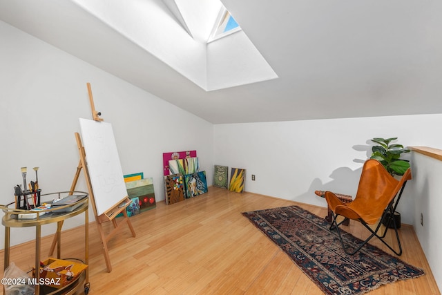 rec room with hardwood / wood-style flooring and lofted ceiling with skylight