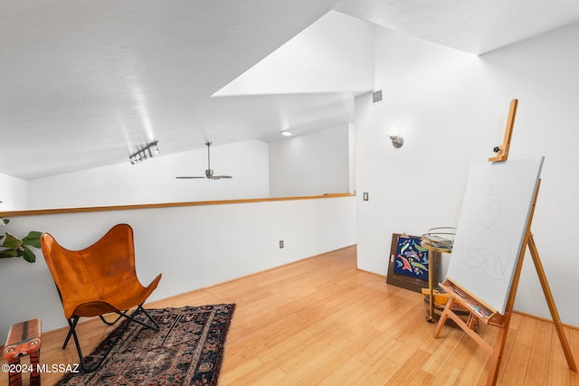 living area with hardwood / wood-style floors, ceiling fan, and vaulted ceiling