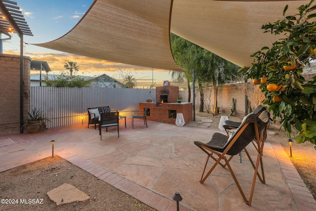 patio terrace at dusk featuring an outdoor brick fireplace