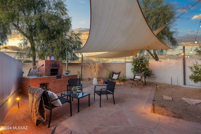 patio terrace at dusk featuring an outdoor brick fireplace