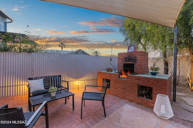 patio terrace at dusk with an outdoor living space with a fireplace